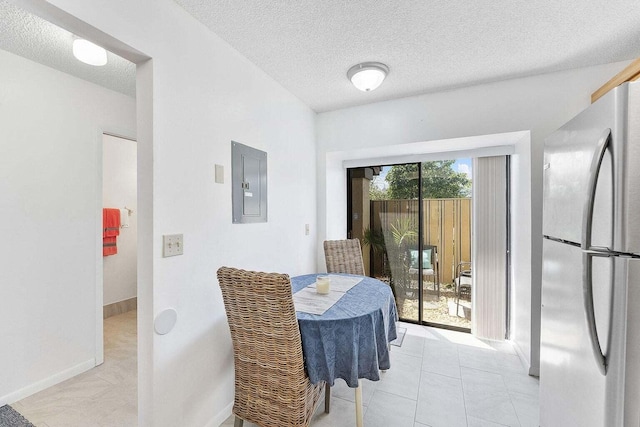 dining space with baseboards, a textured ceiling, light tile patterned floors, and electric panel