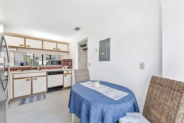 dining area featuring electric panel, a textured ceiling, and visible vents
