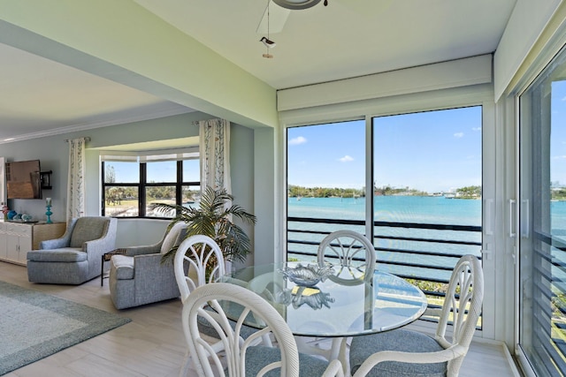interior space with crown molding, a water view, ceiling fan, and light wood finished floors