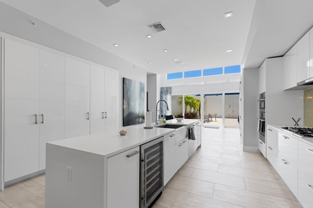 758 N St, West Palm Beach, FL 33401 - kitchen featuring wine cooler, modern cabinets, a sink, a large island with sink, and white cabinetry