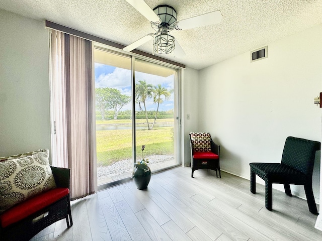 7145 Huntington Ln Unit 102, Delray Beach, FL 33446 - sitting room with a textured ceiling, visible vents, ceiling fan, light wood finished floors, and a water view