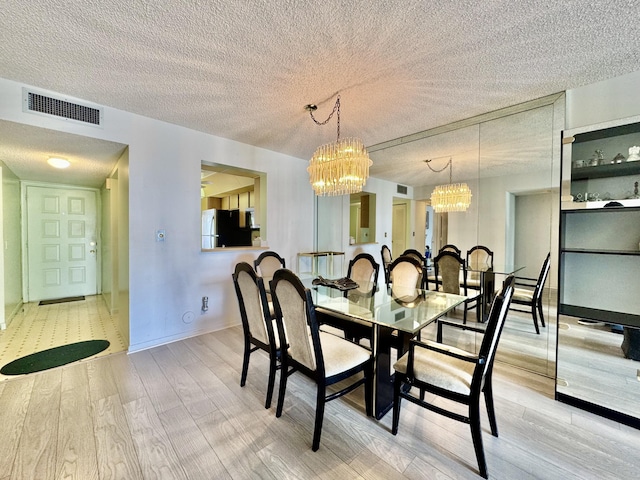 7145 Huntington Ln Unit 102, Delray Beach, FL 33446 - dining room with an inviting chandelier, visible vents, a textured ceiling, and wood finished floors