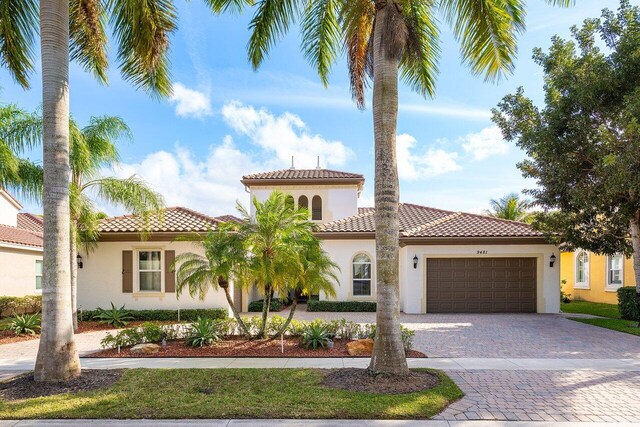 9481 Mcaneeny Ct, Wellington, FL 33414 - mediterranean / spanish house featuring stucco siding, a garage, decorative driveway, and a tile roof