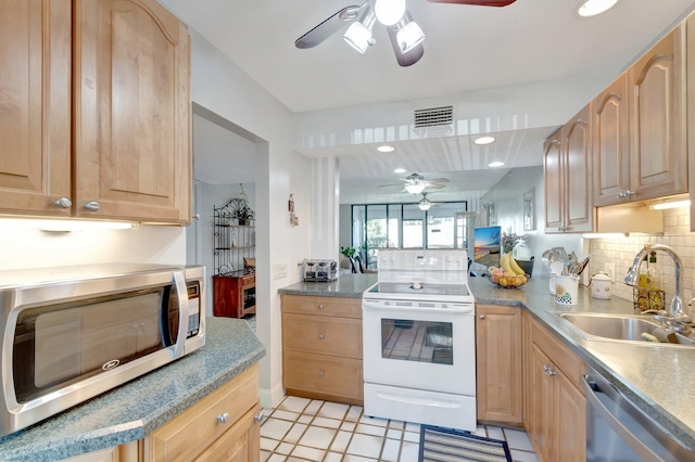 kitchen featuring appliances with stainless steel finishes, a ceiling fan, a sink, backsplash, and light brown cabinetry