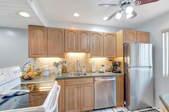 kitchen featuring appliances with stainless steel finishes, a sink, light brown cabinets, a ceiling fan, and decorative backsplash