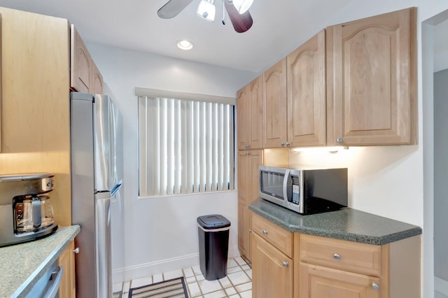 kitchen with stainless steel appliances, light brown cabinetry, a ceiling fan, baseboards, and dark countertops