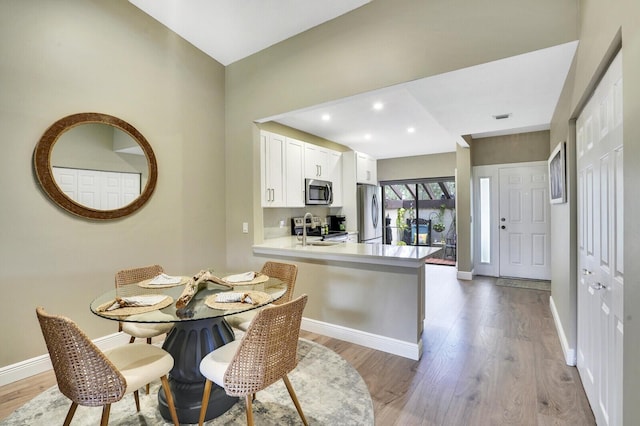 kitchen featuring stainless steel appliances, baseboards, light wood finished floors, white cabinetry, and light countertops