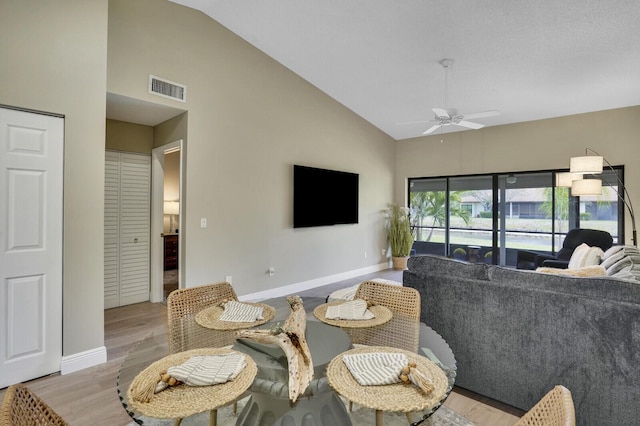 living room featuring baseboards, visible vents, high vaulted ceiling, and a ceiling fan