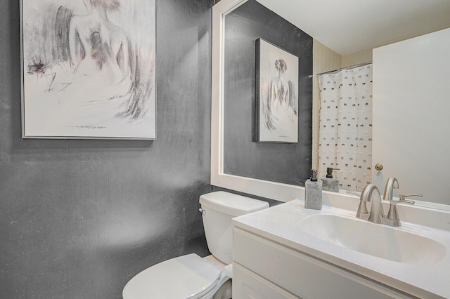 bathroom featuring toilet, vanity, and a shower with curtain