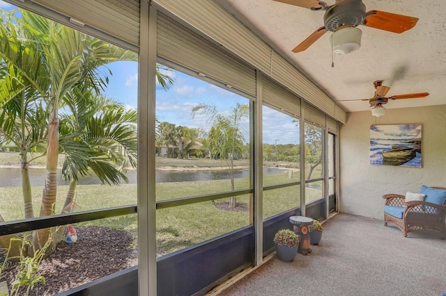sunroom featuring a water view and a ceiling fan