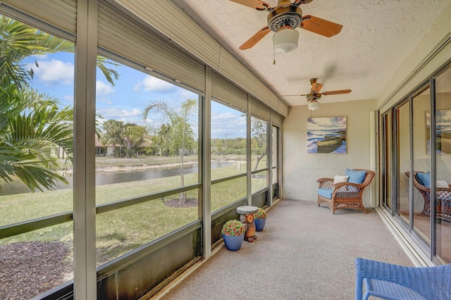 sunroom / solarium featuring ceiling fan and a water view