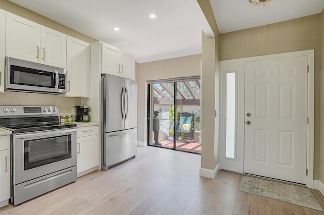 kitchen with light wood-style flooring, white cabinetry, light countertops, baseboards, and appliances with stainless steel finishes