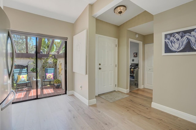 entryway with baseboards, arched walkways, and light wood-style floors