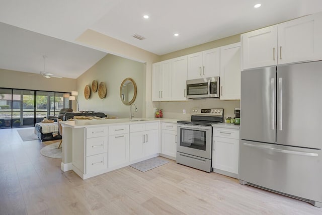 kitchen featuring light wood finished floors, stainless steel appliances, open floor plan, and visible vents