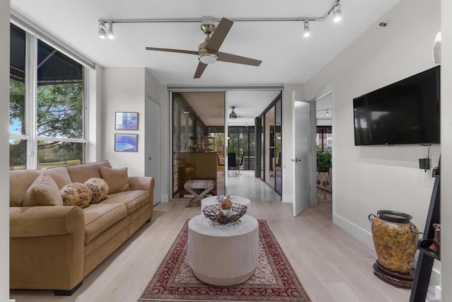 living room with rail lighting, ceiling fan, light wood-style floors, and baseboards
