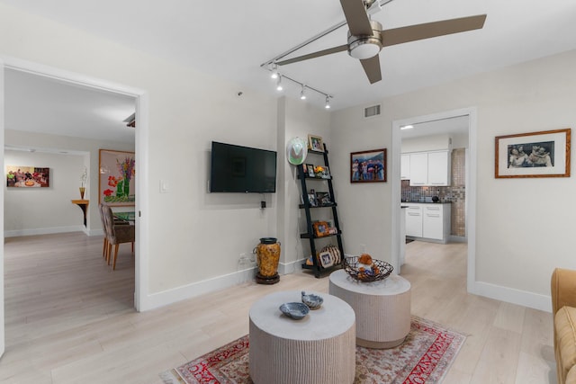 living area featuring ceiling fan, light wood-type flooring, baseboards, and track lighting