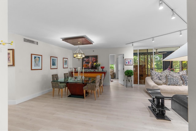 dining area with rail lighting, wood finished floors, a chandelier, and baseboards