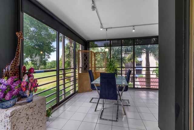 sunroom with expansive windows, track lighting, and tile patterned flooring