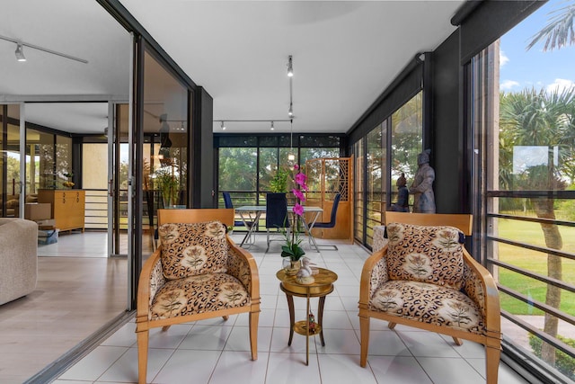 sunroom featuring track lighting, a wall of windows, and tile patterned floors