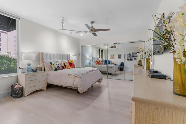 bedroom with rail lighting, light wood-type flooring, and a ceiling fan