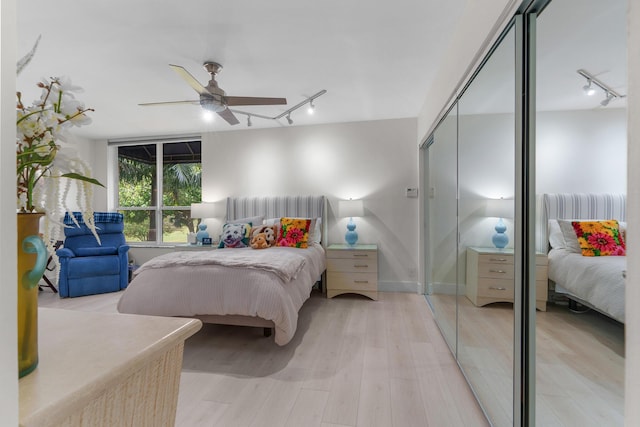 bedroom featuring track lighting, a closet, light wood-style flooring, and a ceiling fan