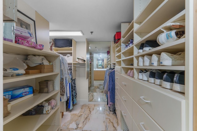 walk in closet featuring marble look tiles