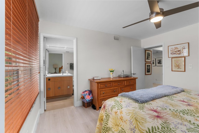 bedroom featuring light wood-style floors, ensuite bath, and a ceiling fan