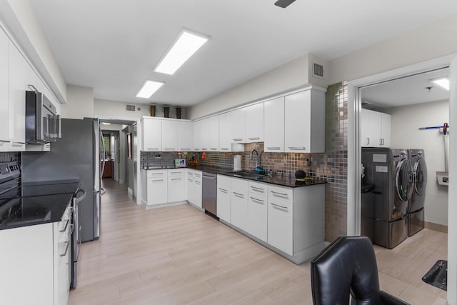 kitchen with separate washer and dryer, appliances with stainless steel finishes, a sink, dark countertops, and tasteful backsplash