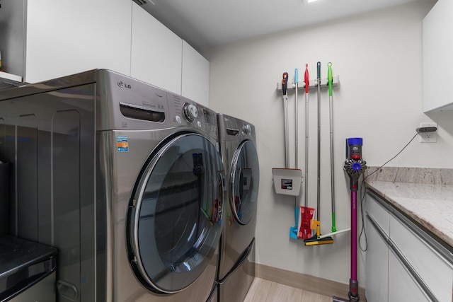 washroom featuring independent washer and dryer, cabinet space, and baseboards