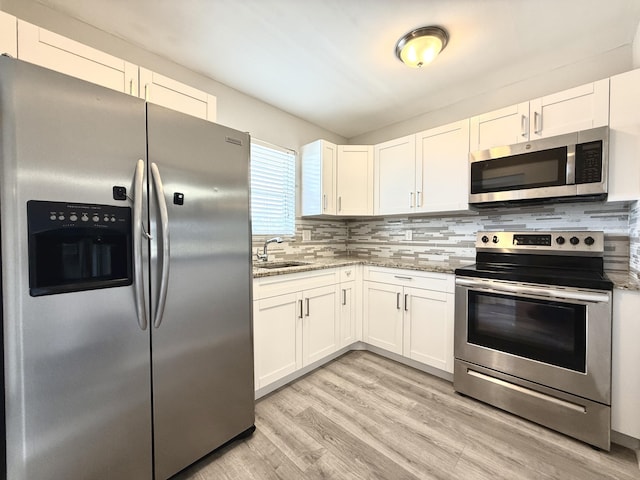 kitchen featuring light wood finished floors, decorative backsplash, white cabinets, and appliances with stainless steel finishes