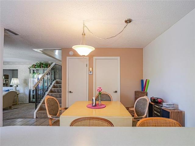 dining area featuring a textured ceiling, visible vents, and stairs