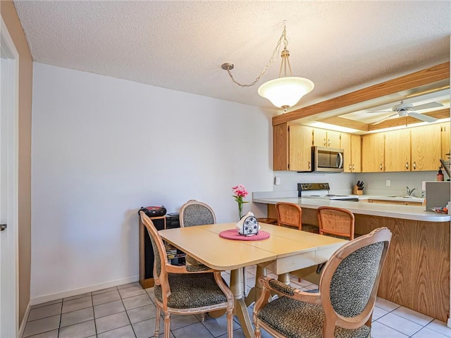 dining area with light tile patterned floors, baseboards, ceiling fan, and a textured ceiling