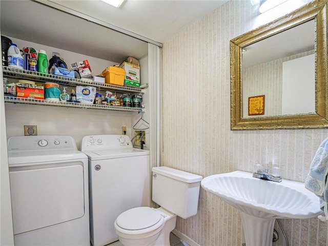 bathroom featuring separate washer and dryer, wallpapered walls, toilet, and a sink