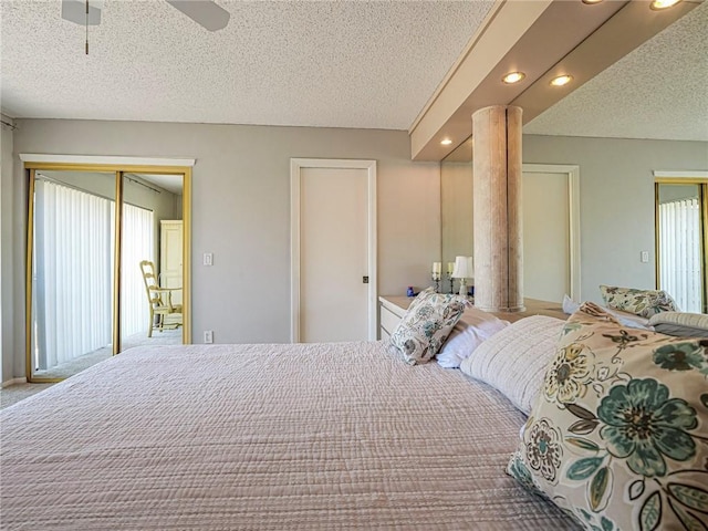 bedroom featuring a textured ceiling, ornate columns, recessed lighting, two closets, and a ceiling fan