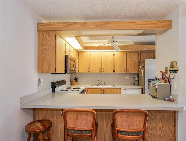 kitchen featuring a peninsula, light countertops, appliances with stainless steel finishes, and a sink