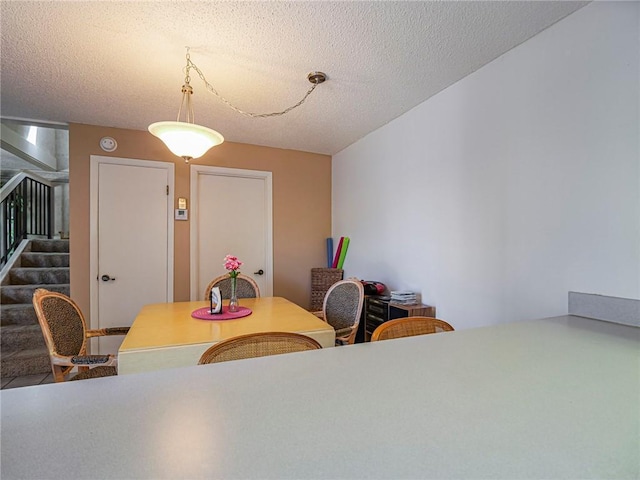 dining space featuring a textured ceiling and stairway