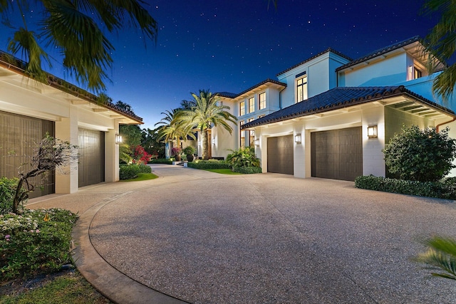 232 Bears Club Dr, Jupiter, FL 33477 - property exterior at night featuring driveway, a tiled roof, and an attached garage
