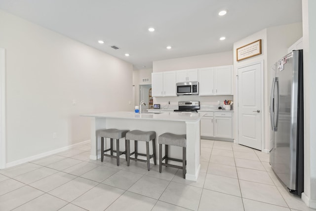 4235 Troon Pl, Fort Pierce, FL 34947 - kitchen featuring appliances with stainless steel finishes, a sink, white cabinets, a breakfast bar area, and light countertops