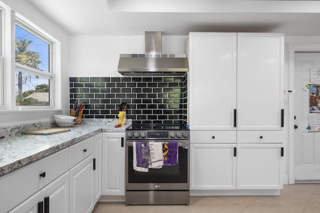2426 SE Stonecrop St, Port Saint Lucie, FL 34984 - kitchen with wall chimney range hood, white cabinetry, backsplash, light tile patterned floors, and electric range