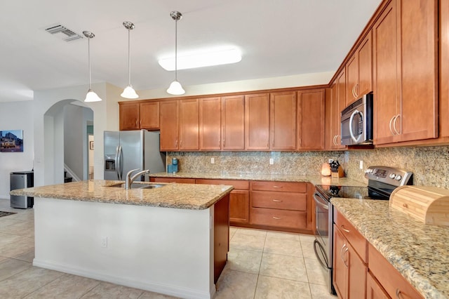 6805 Osage Cir, Greenacres, FL 33413 - kitchen with stainless steel appliances, a sink, arched walkways, decorative backsplash, and brown cabinets