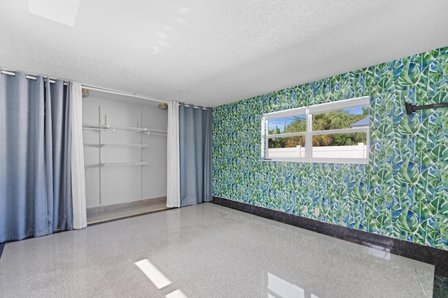 2650 NE 22nd St, Pompano Beach, FL 33062 - spare room featuring wallpapered walls, baseboards, a textured ceiling, and speckle patterned floor