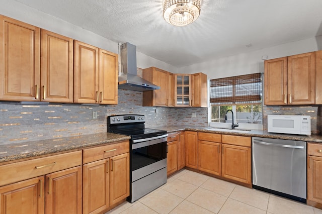 2650 NE 22nd St, Pompano Beach, FL 33062 - kitchen with appliances with stainless steel finishes, wall chimney exhaust hood, a sink, dark stone counters, and light tile patterned flooring