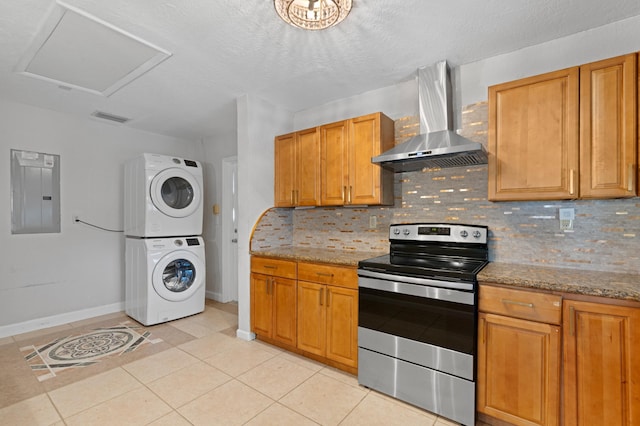 2650 NE 22nd St, Pompano Beach, FL 33062 - kitchen with stainless steel range with electric stovetop, wall chimney exhaust hood, estacked washer and dryer, electric panel, and backsplash