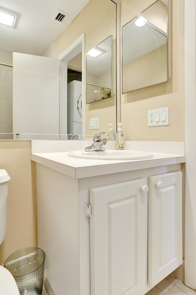 1961 SW 15th St Unit 82, Deerfield Beach, FL 33442 - bathroom with estacked washer and dryer, toilet, vanity, and tile patterned floors