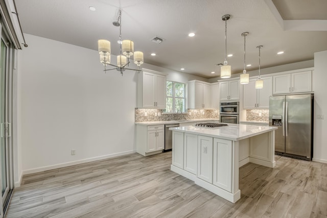 179 Tresana Blvd Unit 145, Jupiter, FL 33478 - kitchen with appliances with stainless steel finishes, light countertops, tasteful backsplash, light wood-style floors, and a kitchen island