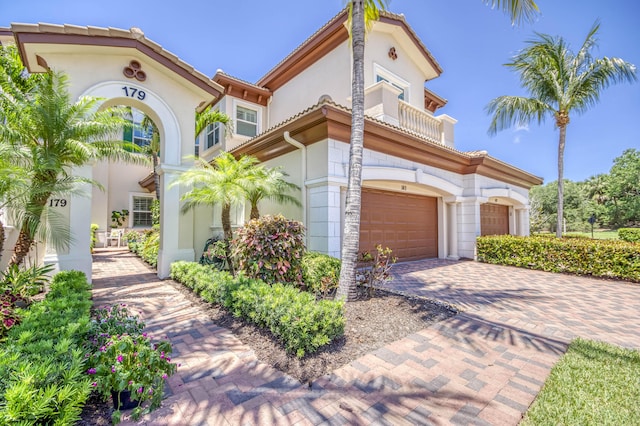 179 Tresana Blvd Unit 145, Jupiter, FL 33478 - mediterranean / spanish house featuring a balcony, decorative driveway, an attached garage, and stucco siding