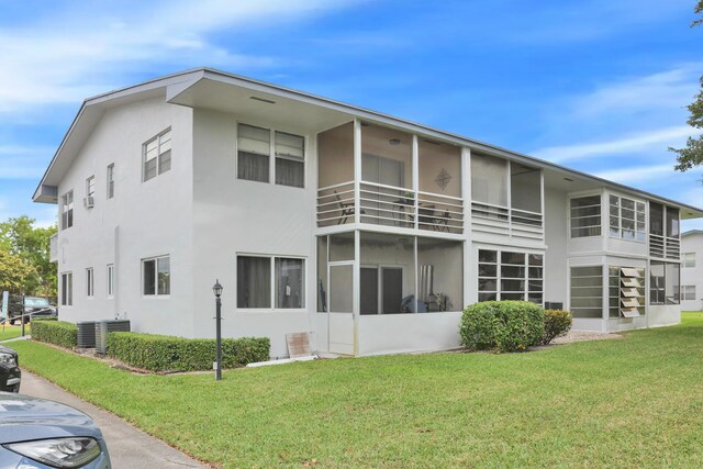 rear view of property with stucco siding, a lawn, and central AC unit