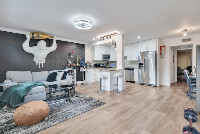 living area featuring crown molding, light wood-type flooring, and recessed lighting