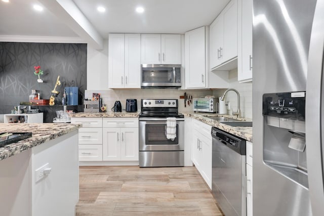 kitchen featuring appliances with stainless steel finishes, a sink, backsplash, recessed lighting, and light stone counters