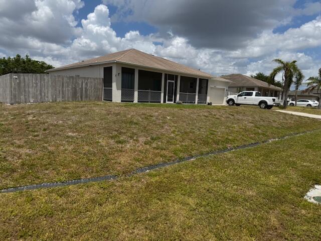 exterior space featuring a yard, a sunroom, a garage, and fence